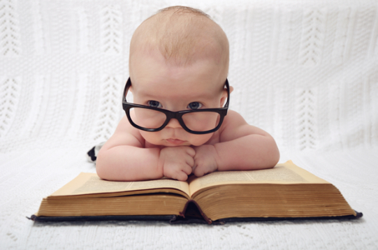 Baby mit Brille liest ein Buch